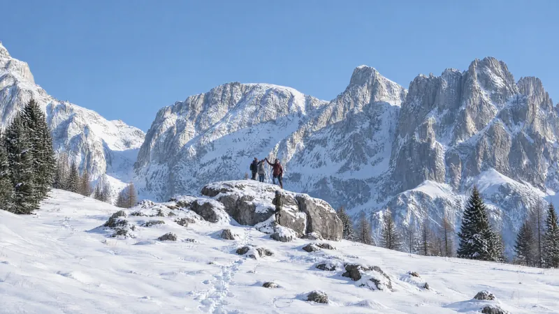 Familie jubelt auf einem verschneiten Gipfelfelsen vor den Mandlwänden am Hochkönig